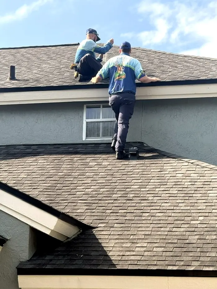 Forest Pest technicians on the roof of a home repairing vents